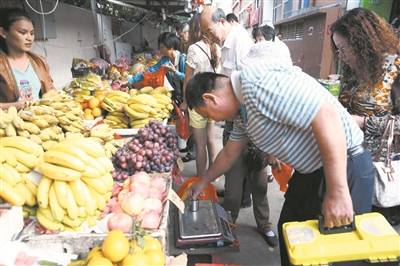 天涯区执法人员检查水果摊上的秤具